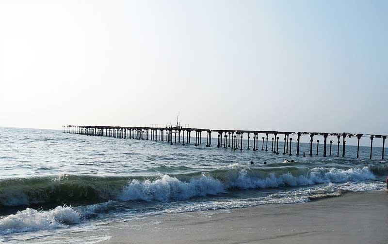 Waves rolling toward the beach beside the old pier