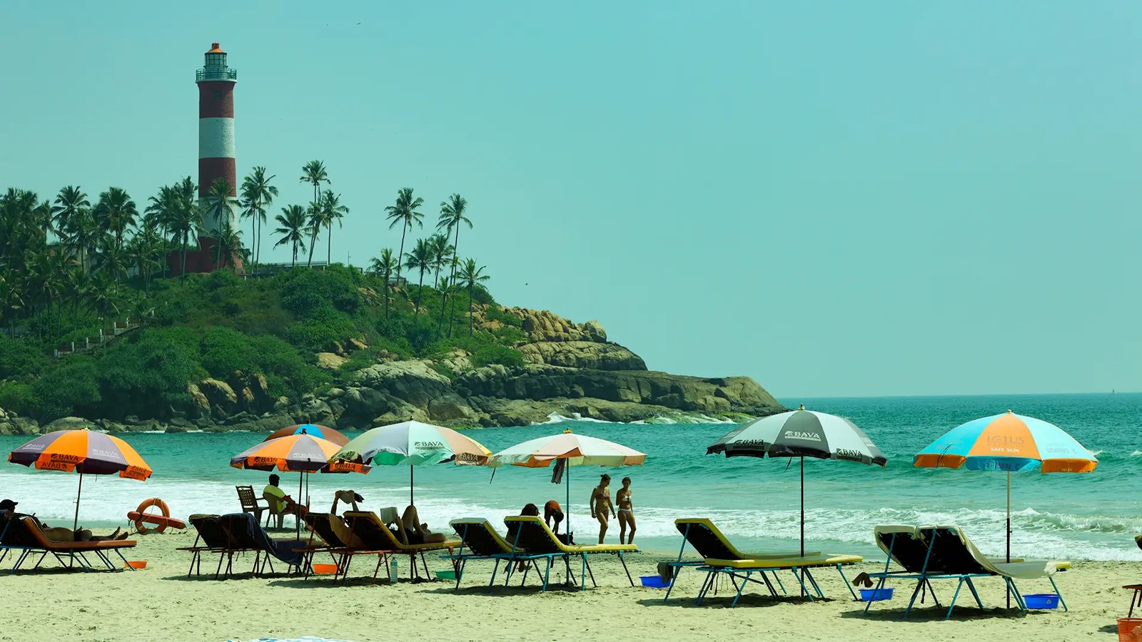 Beach umbrellas and boats beneath the Kovalam lighthouse