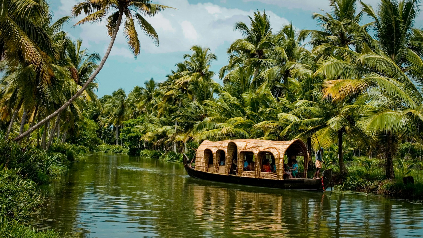 A houseboat gliding through the palm-lined backwaters of Kerala